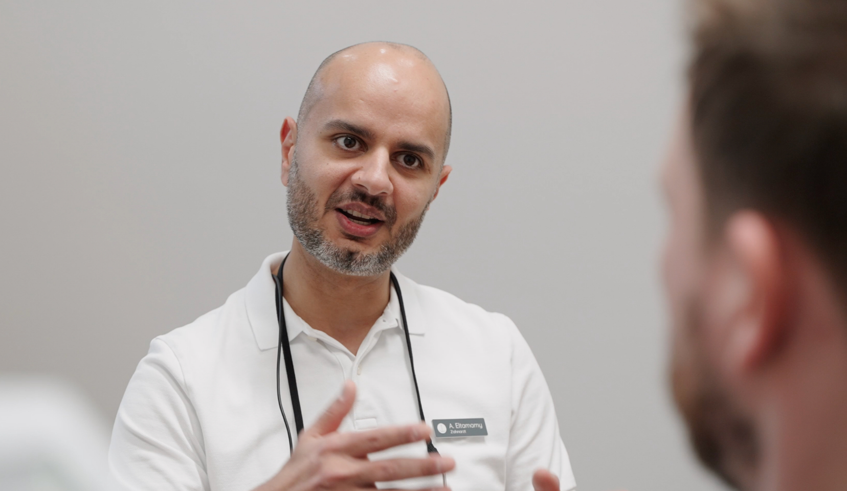 Ahmed Eltamamy im Beratungsgespräch mit einem Patienten in der Praxis ANKERZAHN